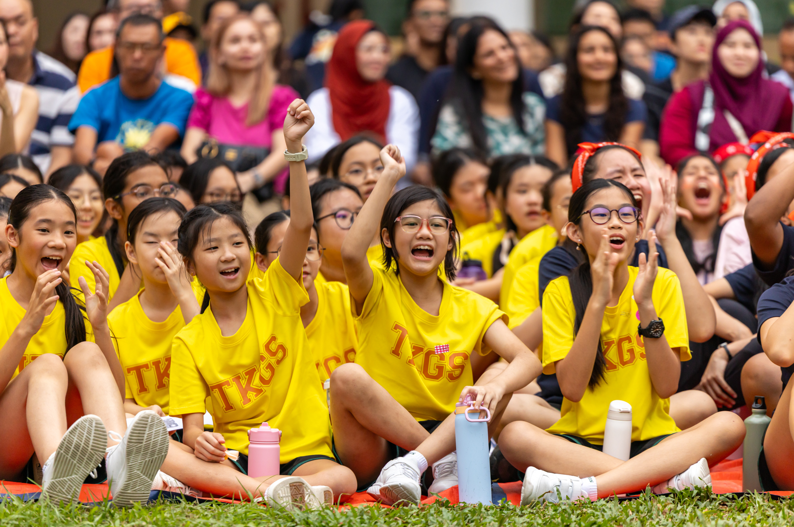 Students in yellow shirts cheering loudly for their school mates.